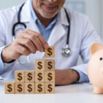 A male doctor in a white coat stacking wooden blocks with dollar signs