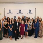 Bethany Insurance employees pose in front of a Bethany Insurance backdrop at the agency's 20th anniversary party