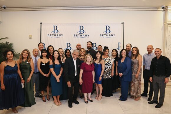 Bethany Insurance employees pose in front of a Bethany Insurance backdrop at the agency's 20th anniversary party