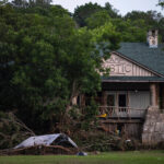 Flood debris piled around a damaged cabin at Camp Mystic in Hunt, Texas