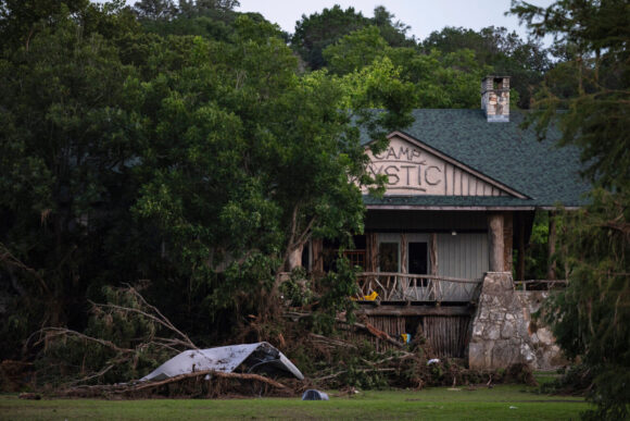 Flood debris piled around a damaged cabin at Camp Mystic in Hunt, Texas