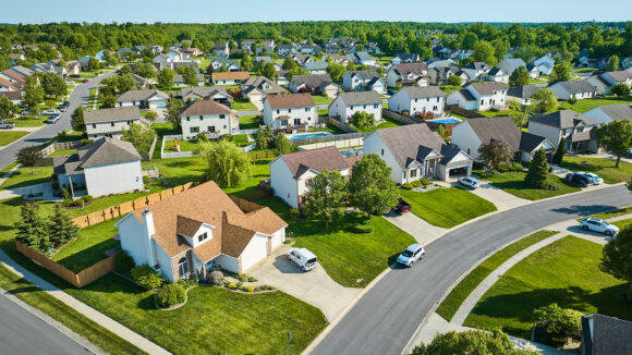 Aerial view of a suburban neighborhood of two-story homes with cars in the driveways