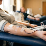 Patient donating blood in a clinic, with a blood bag and IV tubing in the foreground