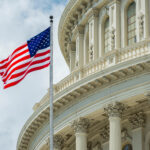 American flag waving in front of the U.S. Capitol dome in Washington, D.C.