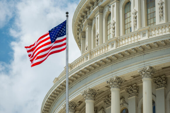 American flag waving in front of the U.S. Capitol dome in Washington, D.C.