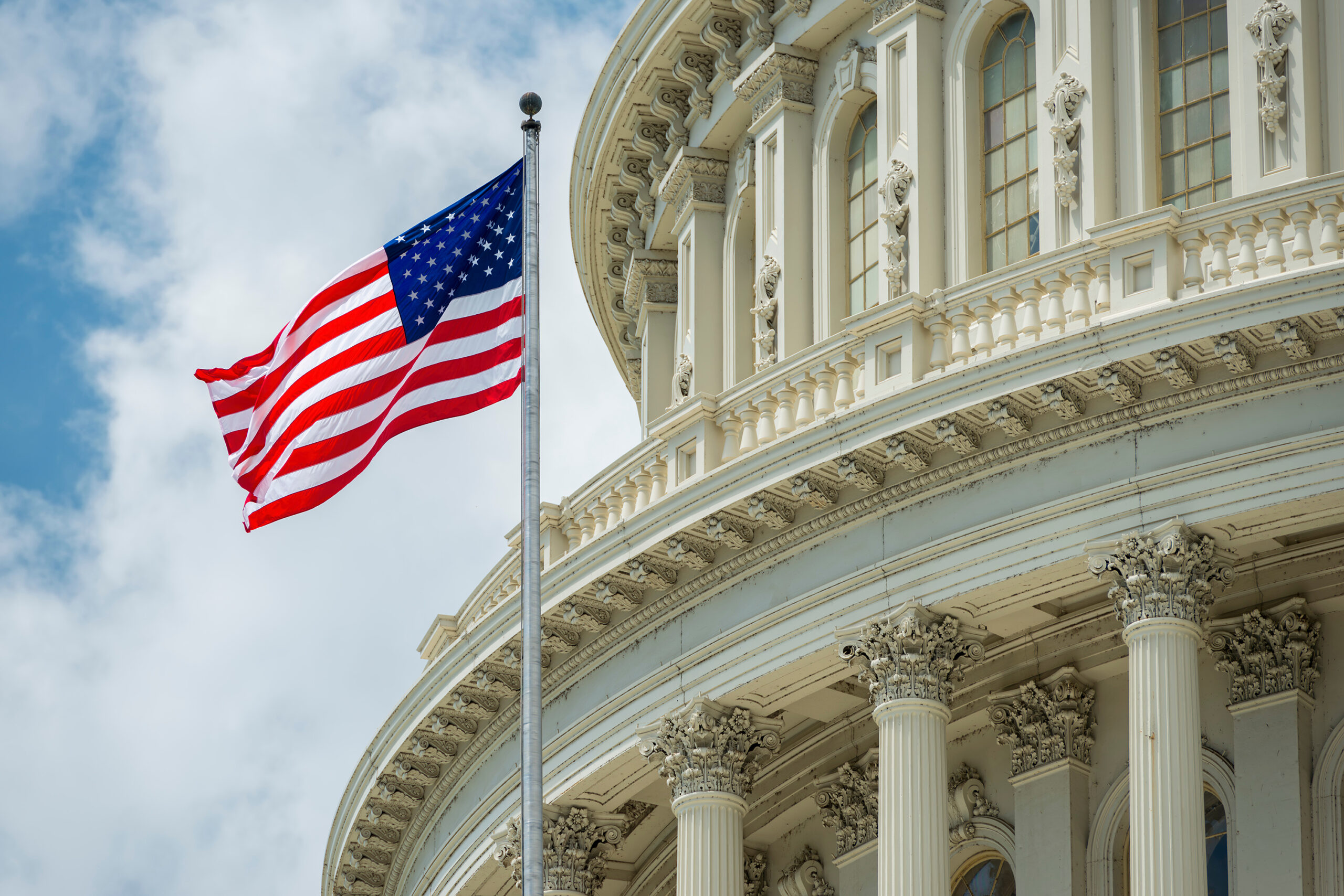 American flag waving in front of the U.S. Capitol dome in Washington, D.C.