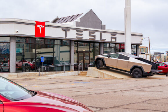 Tesla dealership with a red Tesla sign and a Cybertruck parked out front