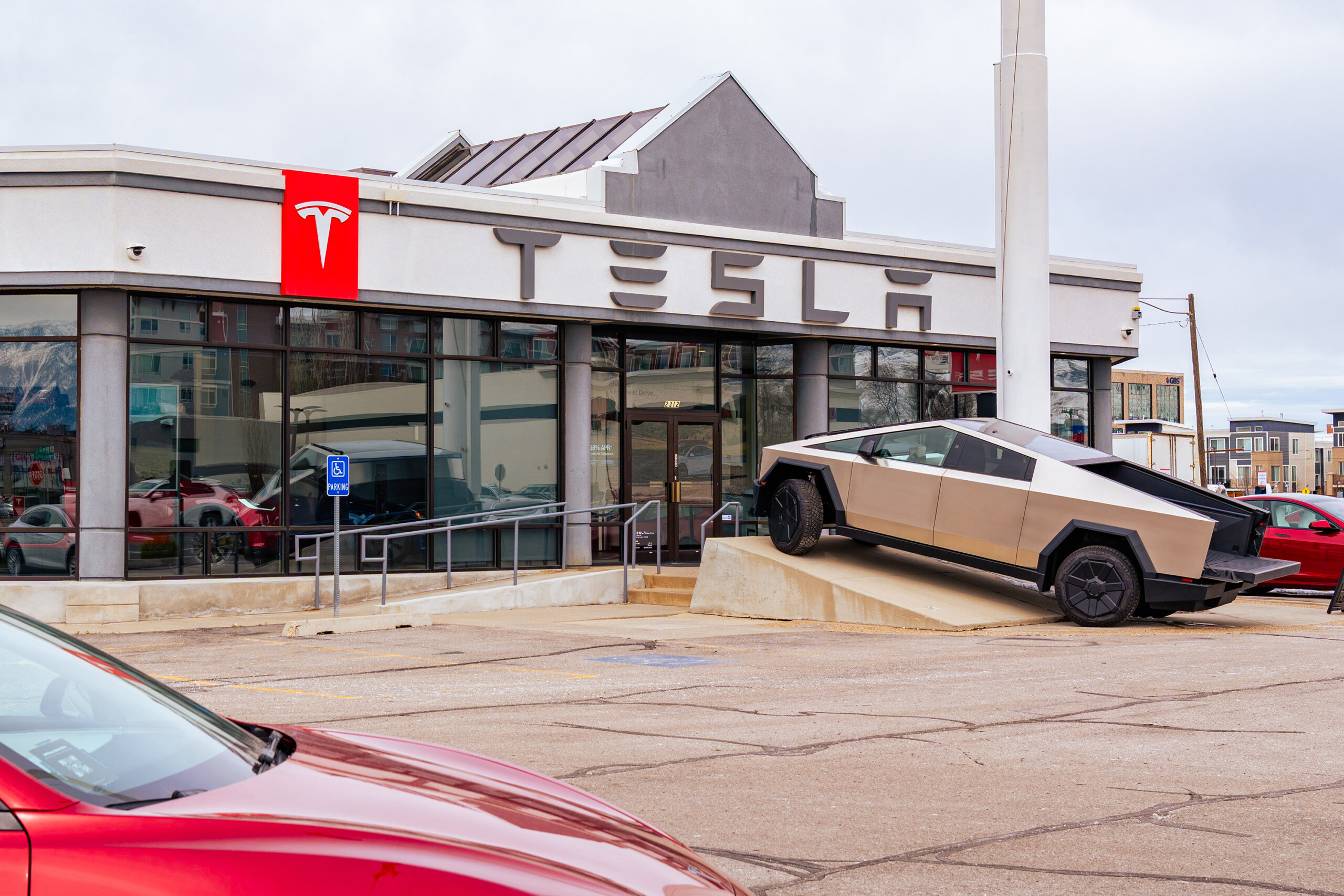 Tesla dealership with a red Tesla sign and a Cybertruck parked out front
