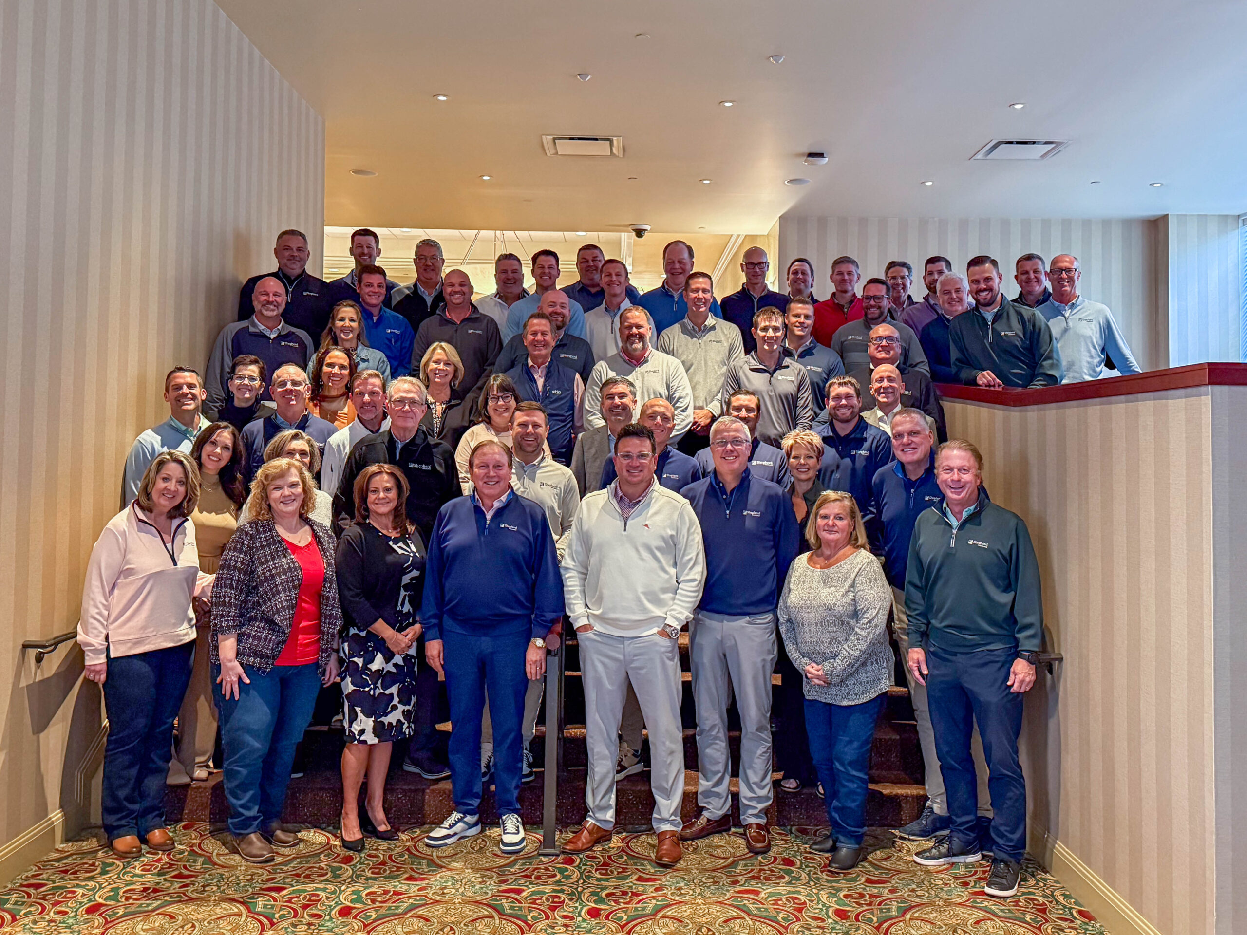 Shepherd Insurance employees pose for a large group photo on a staircase
