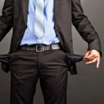 A businessman in a suit pulling out his empty pants pockets