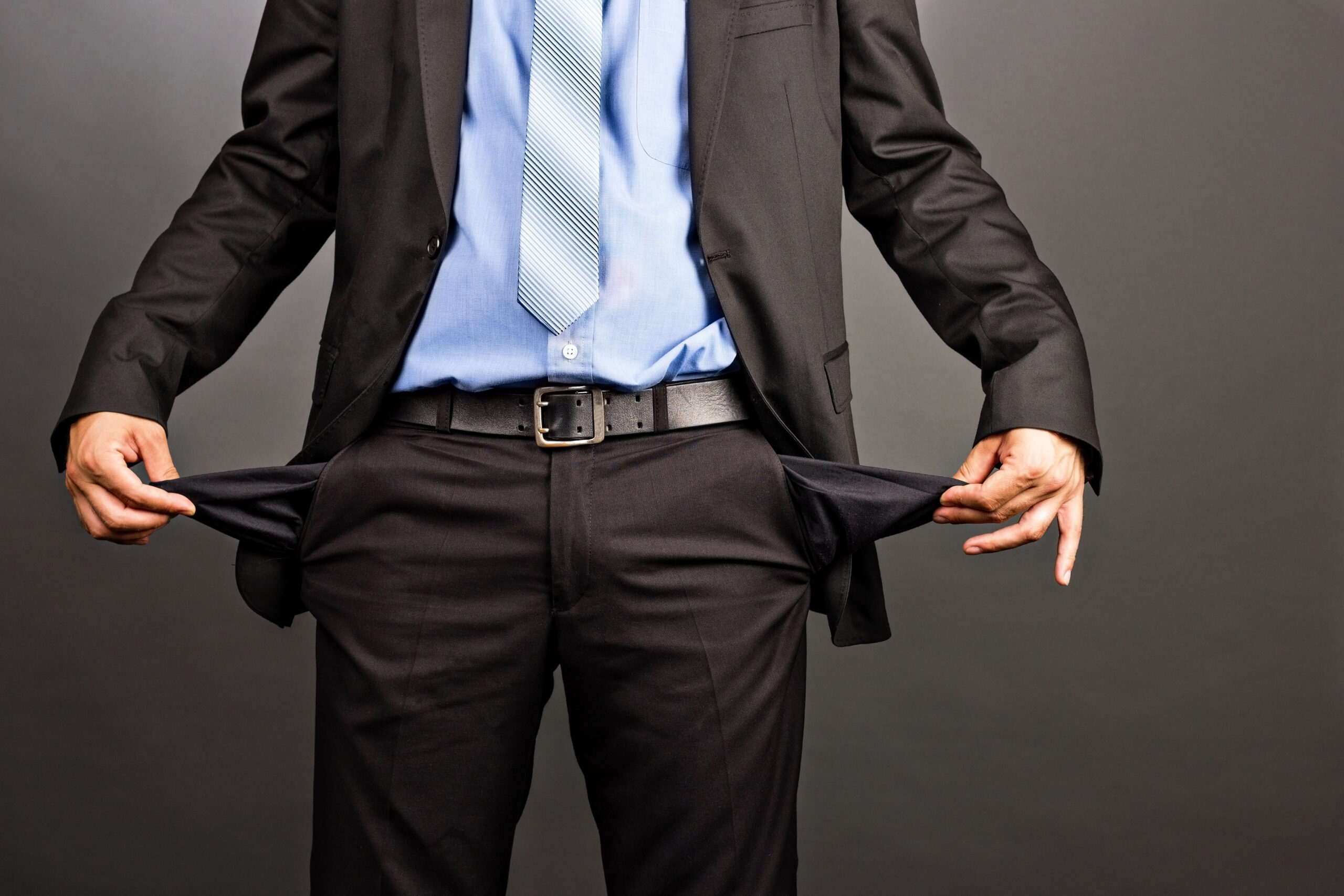 A businessman in a suit pulling out his empty pants pockets